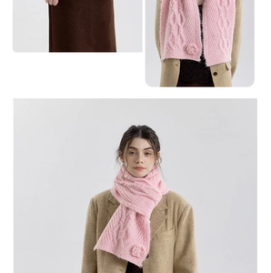 Detail of pink cable knit scarf featuring 3D floral accents and thick woven texture