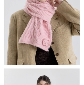 Detail of pink knitted scarf featuring chunky cable patterns and a crochet flower accent