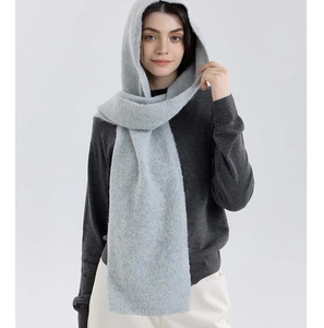 Detail of light blue-grey knitted hooded scarf showing soft thick texture on a model