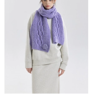 Close-up detail of purple cable-knit scarf featuring a hand-crocheted 3D flower accent