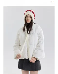 Detail of white knitted trapper hat with red heart patterns and long hanging straps