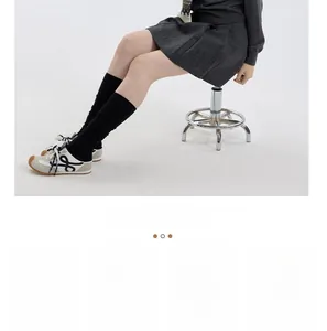 Detail of gray pleated skirt paired with black over-the-knee socks and vintage sneakers