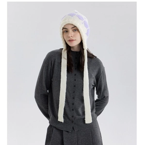 Detail of cream knit earflap hat with lavender patterns and stylish long braided tassels