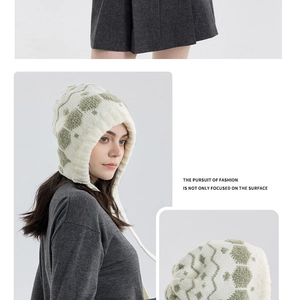 Detail of knit snowflake beanie with earflaps showing olive green sheep patterns