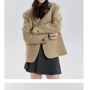 Detail of khaki wool blazer fabric texture and dark buttons on a stylish winter outfit