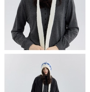 Close-up of blue and white snowflake pattern knit hat with soft earflaps and grey cardigan