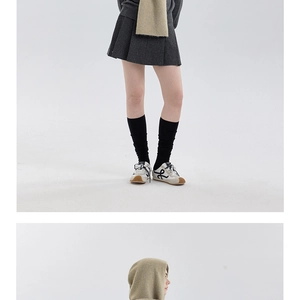 Detail view of khaki knitted hooded scarf and dark grey pleated skirt outfit for winter