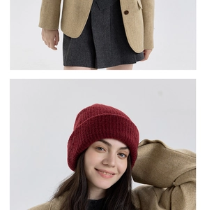 Detail of red thick wool knit hat paired with beige herringbone blazer for winter style