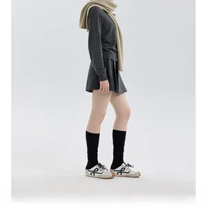 Deep grey knit sweater set and pleated skirt styled with light beige hooded scarf detail