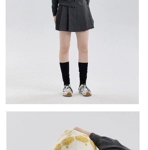 Detail of a grey pleated skirt paired with retro sneakers and black socks on a model