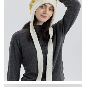 Detail of cream knit snowflake hat with yellow patterns and stylish side straps