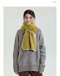 Close-up of green knit scarf with contrast white trim and grey oversized sweater