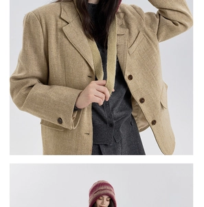 Detail van visgraat blazer gecombineerd met een gestreepte gebreide muts voor de winter