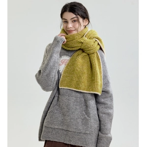 Close-up of thick green chunky knit scarf paired with a grey sweater for winter style