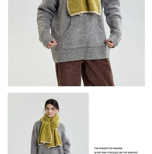 Close-up of thick knit mustard yellow scarf with contrasting cream-colored edges