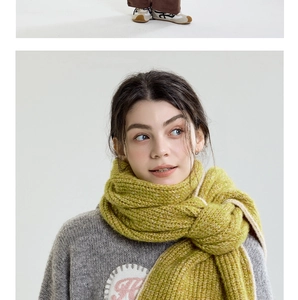 Close-up texture of a thick grass green knit scarf and a vintage embroidered sweater