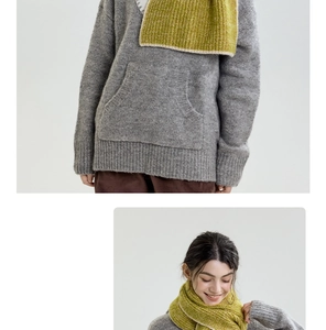 Detail of grey knit sweater with kangaroo pocket and green contrast hem scarf