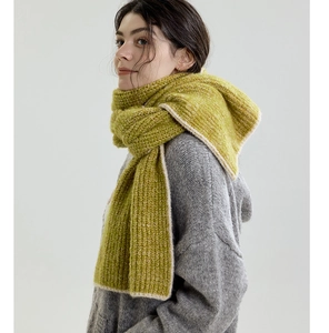 Close-up of chunky knit winter scarf with contrast beige edges and avocado green texture