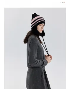 Dettaglio cappello in maglia con paraorecchie, strisce rosa e lacci lunghi in mohair