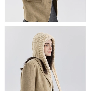 Detail der Strickstruktur einer cremefarbenen Kapuzenmütze mit geflochtenen Trägern