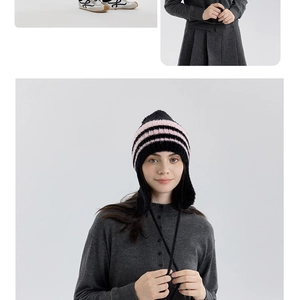 Dettaglio del cappello in maglia a righe con paraorecchie e pompon decorativo