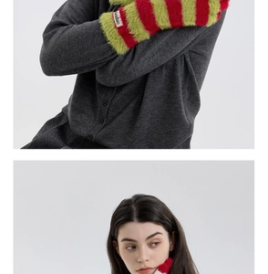 Detail of fuzzy red and green striped arm warmers with plush texture and woven label