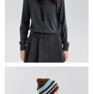 Dettaglio della trama del cardigan grigio scuro e del berretto in lana a righe blu invernali
