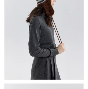 Dettaglio del cappello in maglia a righe marroni e azzurre con caldi copriorecchie