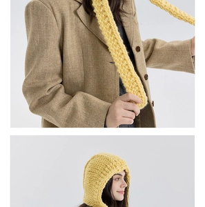 Detailansicht einer gelben handgestrickten Kapuze mit langen Bändern zum Festbinden