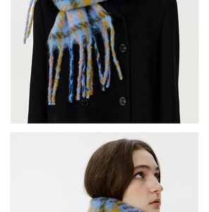 Detail of blue and yellow plaid scarf with thick tassels on a black wool coat