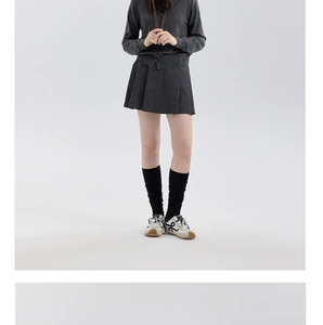 Dettaglio di un completo in maglia grigia con cardigan e gonna a pieghe in tessuto misto