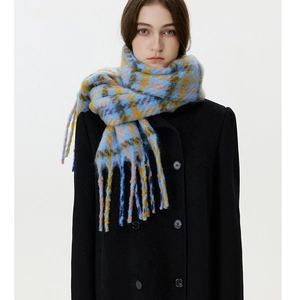 Detail of colorful plaid scarf with long fringes worn over a black double-breasted coat