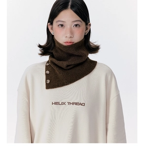 Detail view of brown knitted neck warmer with three decorative buttons on white sweatshirt