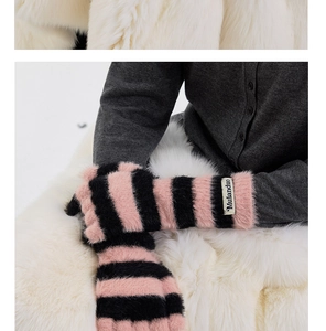 Close-up of pink and black striped plush gloves with a fuzzy texture and woven brand label