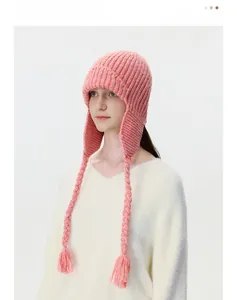 Detail of pink knitted trapper hat featuring braided tassels and thick wool texture