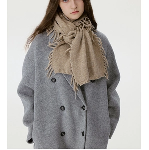 Nahaufnahme eines weichen beigen Fransenschals mit grauem Wollmantel für den Winter