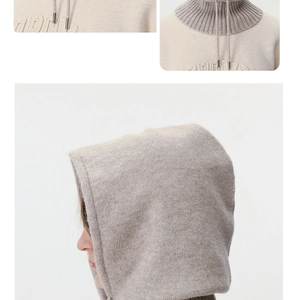 Detail of beige knitted balaclava with ribbed collar, drawstrings, and subtle embroidery