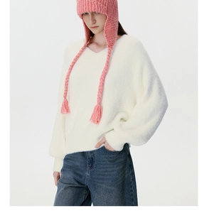 Detailed close-up of pink cable knit trapper hat with long braided earflaps and tassels