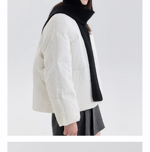 Close-up of stylish white quilted down jacket with thick black knit hooded scarf detail