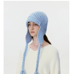 Detailed knit of a light blue winter trapper hat featuring braided earflap tassels