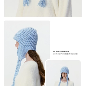 Close-up of light blue knit trapper hat with thick braids and warm ribbed texture details