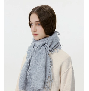 Detailansicht der hellgrauen Strickschal-Textur mit Fransen-Quasten für den Winter