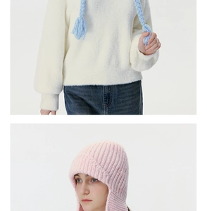 Close-up of cable knit winter ear-protection hat with braided tassels and soft fuzzy texture