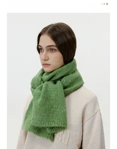 Detailed knit texture of a warm wool blend matcha green scarf tied around the neck