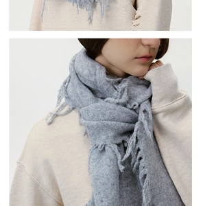 Detail eines weichen grauen Strickschals mit Fransenstruktur und flauschigem Finish
