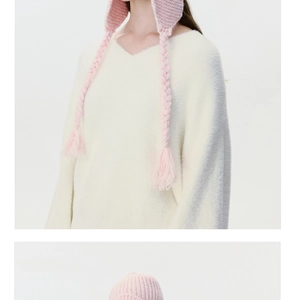 Detailed knit texture of pink ear flap hat with braided tassels for winter warmth