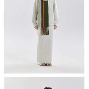Detail of wool blend striped scarf with tassels paired with a beige knit outfit
