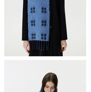 Detail of blue and black plaid wool scarf with fringe and letters on knit texture