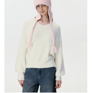 Detail of pink cable knit earflap hat with braids and soft white V-neck sweater