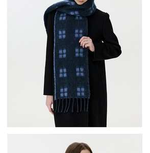 Detail of blue and black plaid wool scarf featuring soft texture and twisted tassels
